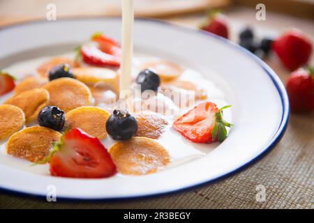 Minipancakes céréales dans un bol avec lait et fruits Banque D'Images