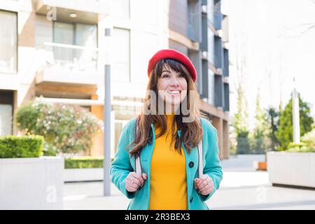 Femme souriante portant un sac à dos devant le bâtiment Banque D'Images