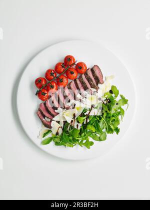 Steak Tagliata avec tomates cerises, arugula et parmesan Banque D'Images