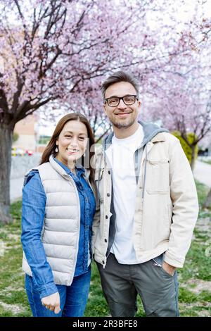 Couple souriant debout devant un cerisier Banque D'Images