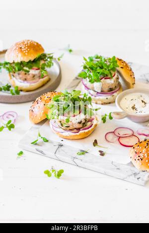 Hamburgers à la patty de poulet avec oignon rouge, radis, moutarde micro-verte et sauce au yaourt Banque D'Images