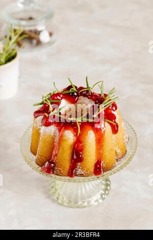 Petit gâteau vanille décoré de sauce aux canneberges et de romarin Banque D'Images