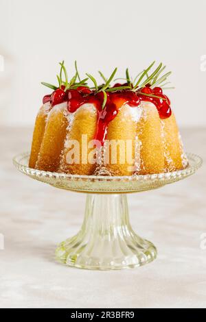 Petit gâteau vanille décoré de sauce aux canneberges et de romarin Banque D'Images
