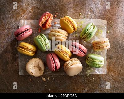 Différents macarons colorés sur papier sur fond de bois Banque D'Images