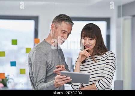 Homme d'affaires pointant vers un collègue au bureau sur un PC tablette Banque D'Images