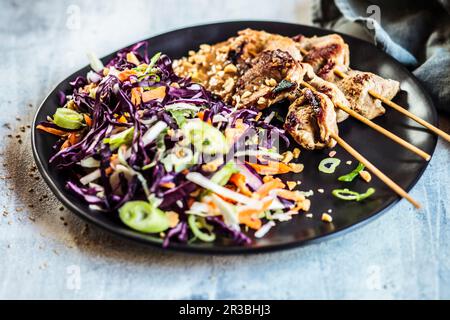 Satay avec une sauce aux arachides et une salade de chou rouge de style thaïlandais Banque D'Images