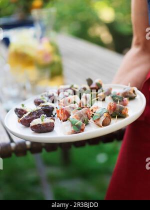 Dattes et châtaignes garnies de bacon sur une assiette de service Banque D'Images