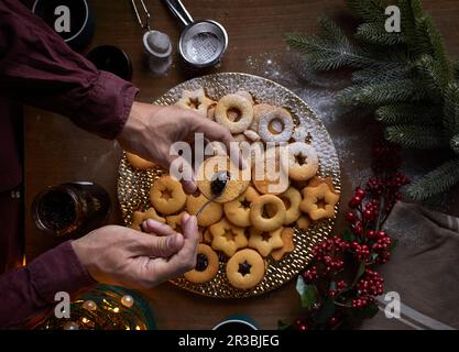 Étaler la confiture sur les biscuits Linzer fraîchement cuits Banque D'Images
