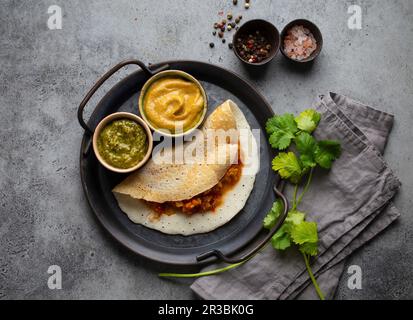 Crêpes traditionnelles de riz indien Dosa avec différentes sauces chutney et assaisonnements Banque D'Images