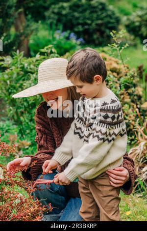 Femme et fils souriants portant des chandails dans le jardin Banque D'Images