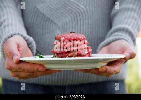 L'homme tient des patties hamburger pour le barbecue Banque D'Images