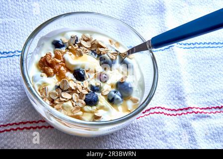Muesli avec flocons d'avoine, noix, yaourt, bleuets et miel Banque D'Images