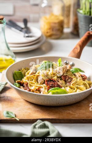 Pâtes tagliatelles avec pesto à l'arugula, poulet et tomates séchées au soleil Banque D'Images