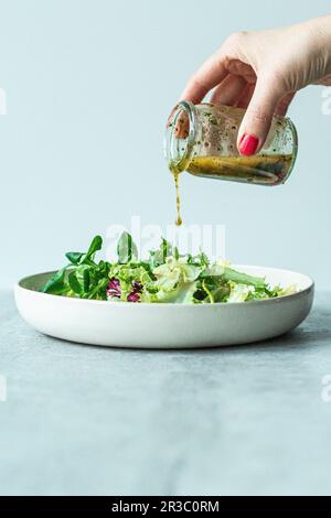 Vinaigrette italienne versée sur une salade Banque D'Images