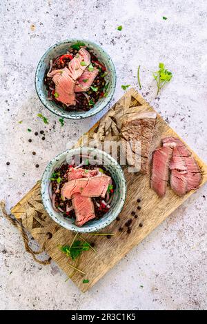 Dans un pot, mettre en salade les lentilles de béluga et les filets de bœuf Banque D'Images