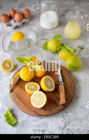 Citrons entiers et coupés en deux sur une planche en bois Banque D'Images