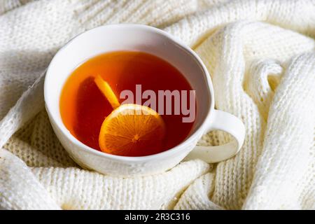Une tasse de thé chaud avec un pull blanc et citron en tant que concept d'hiver Banque D'Images