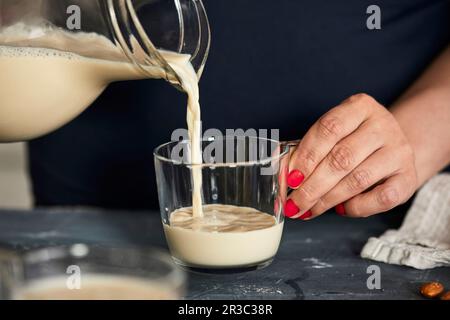 Verser le lait d'amande maison dans un verre Banque D'Images