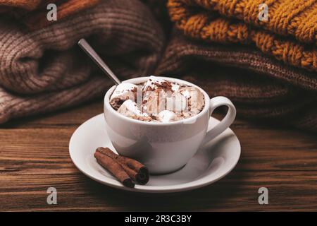 Chocolat chaud avec guimauve et pile de vêtements tricotés chauds Banque D'Images