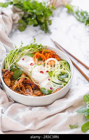 Bol à nouilles de poulet avec courgettes, carottes râpées et herbes fraîches Banque D'Images
