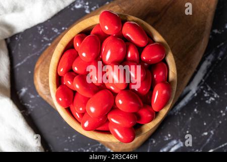 Dragee d'amande au chocolat. Dragee au chocolat rouge dans un bol en bois sur fond sombre. Vue de dessus Banque D'Images