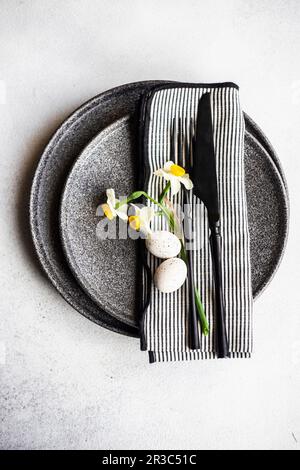 Cadre idéal pour le dîner de Pâques avec fleurs de jonquilles et œufs sur fond de béton Banque D'Images