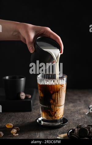 Le lait est versé dans le café glacé Banque D'Images