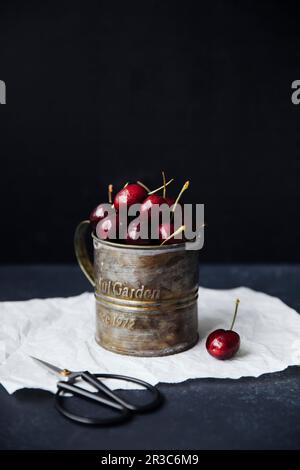 Cerises fraîches dans une tasse en étain vintage Banque D'Images