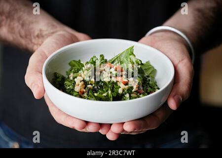 L'orge perlé et la salade verte dans un bol tenu par un serveur Banque D'Images