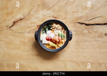 Ramen avec nouilles udon, kimchi, poulet, fromage, œuf, algues et champignons enoki Banque D'Images