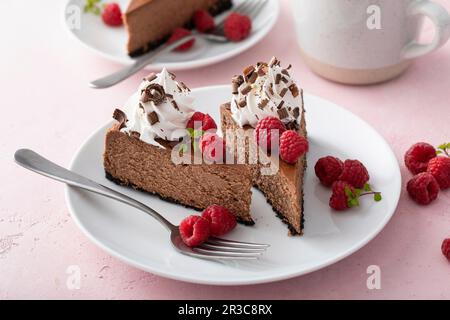 Cheesecake au chocolat à base de biscuit recouvert de crème fouettée, de framboises fraîches et de copeaux de chocolat Banque D'Images