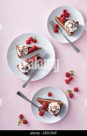 Cheesecake au chocolat à base de biscuit recouvert de crème fouettée, de framboises fraîches et de copeaux de chocolat Banque D'Images