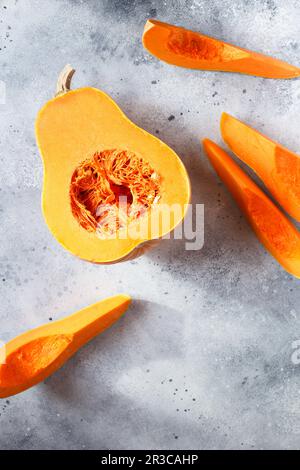 Courge musquée fraîche sur fond gris. Citrouille de noyer cendré. Moitiés de citrouille orange brute. Suite Banque D'Images