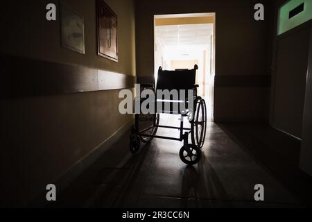 Le fauteuil roulant au milieu d'un couloir vide de l'hôpital Banque D'Images