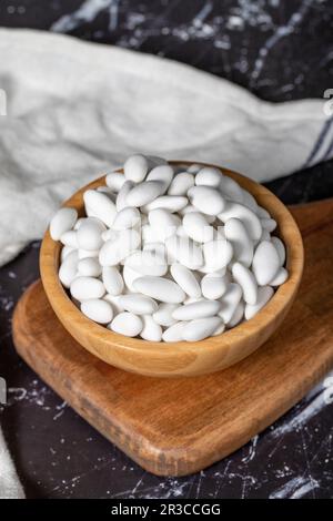 Bonbons aux amandes. Bonbons aux amandes enrobés de sucre dans un bol en bois sur fond sombre. Petites friandises multicolores Banque D'Images