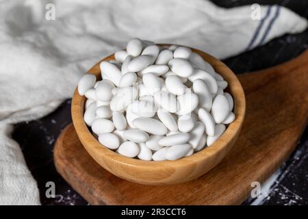 Bonbons aux amandes. Bonbons aux amandes enrobés de sucre dans un bol en bois sur fond sombre. Petites friandises multicolores Banque D'Images