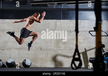 Un homme musclé capturé dans l'air alors qu'il saute dans une salle de sport moderne, mettant en valeur son athlétisme, sa puissance et sa détermination grâce à une forme physique de haute intensité Banque D'Images