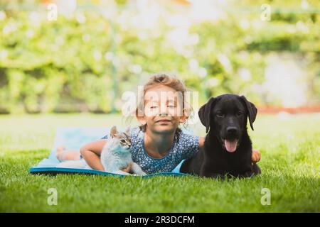 Adorable petite fille joue avec des animaux de compagnie sur l'herbe fraîche Banque D'Images