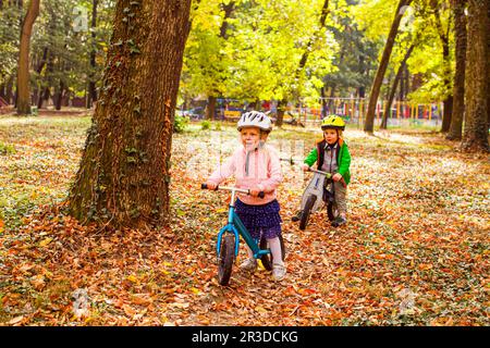 Joyeux enfants d'âge préscolaire à l'extérieur sur des vélos d'équilibre Banque D'Images