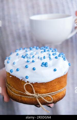 Mains tenir le gâteau de Pâques avec garniture blanche et saupoudrer bleu. Femme tenant un gâteau de Pâques russe traditionnel. Tarte maison pour sp Banque D'Images