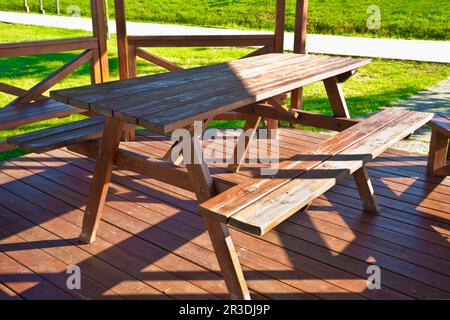 Table de pique-nique en bois dans un belvédère en bois sur un pré vert dans un parc public. Banque D'Images