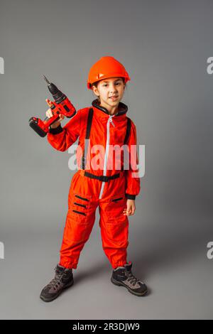 La petite fille vêtue d'un uniforme d'ingénierie rouge tient un tournevis Banque D'Images