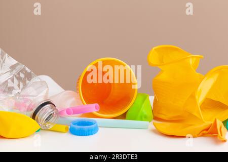 Plastique déchets danger écologie concept avec déchets et pailles colorées à usage unique, tasses à couverts, bouteilles sur fond blanc Banque D'Images