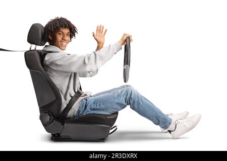 Jeune homme afro-américain dans un siège de conducteur tenant un volant et un agitant isolé sur fond blanc Banque D'Images