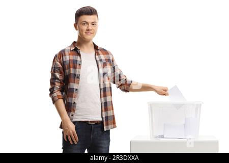 Jeune homme mettant un vote dans une boîte électorale et regardant la caméra isolée sur fond blanc Banque D'Images