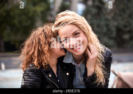 Maman et fille chuchotent tout en marchant dans la ville Banque D'Images