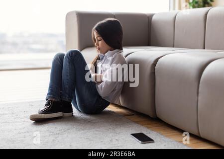 Fille dépressive assise près du téléphone souffrant de dépression à la maison Banque D'Images