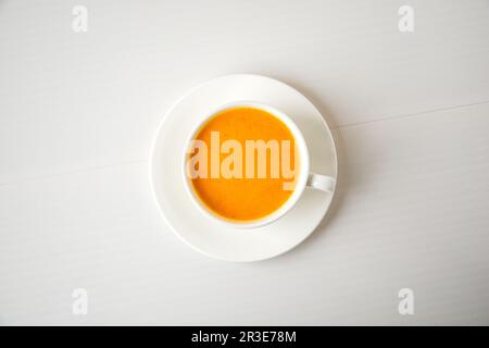 Smoothie à la citrouille, latte aux épices. Cocktail de folie dans une tasse blanche sur fond blanc. Boissons chaudes de saison en automne. Banque D'Images