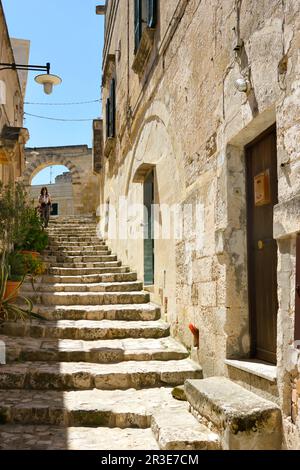 Moments dans la vie quotidienne locale dans le Sassi historique de Matera, Basilicate région de l'Italie. Figure solitaire, descendant sur les escaliers de la vieille rue. Banque D'Images