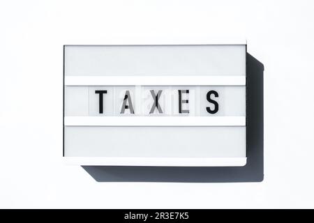 Tableau lumineux sur fond blanc avec les mots TAXS en lettres noires. Banque D'Images